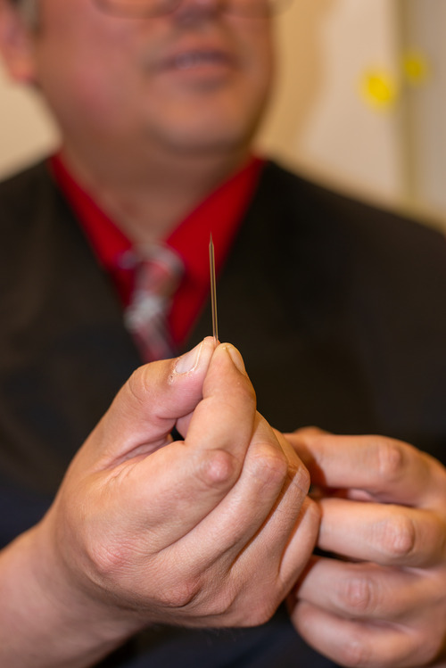 Joseph Neapetung holding a sample micropipette used to pierce neurons.