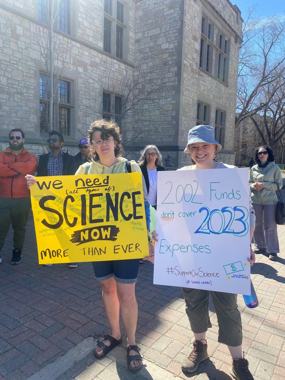 Pictured: Two USask graduate students holding protest signs at the May 1st, 2023 Support Our Science walk-out demonstration