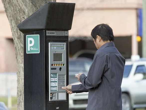 Person paying at a parking kiosk.